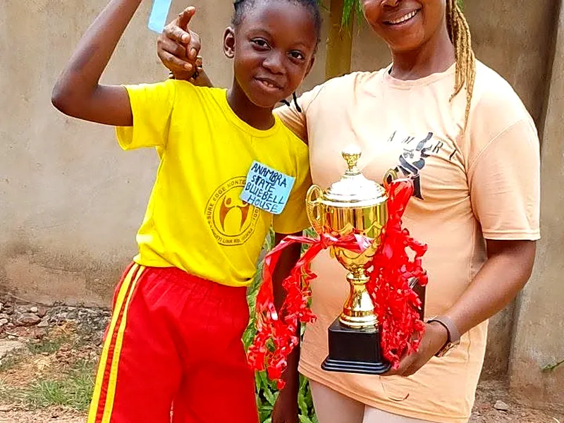 A pupil holding a trophy with a member of staff