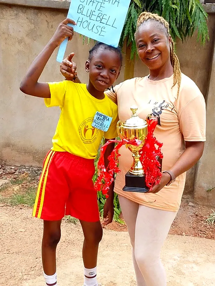 A Sure Edge pupil holding a trophy alongside a member of staff